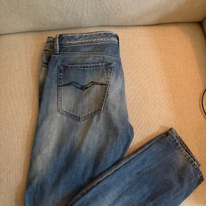 Blå Replay Boyfit jeans, stl 27 - Säljer ett par blå Replay Boyfit jeans i klassisk tvätt med snygga slitningar och detaljer. Jeansen har raka ben, fem fickor och tydliga Replay loggor. Kontakta om du är intresserad.