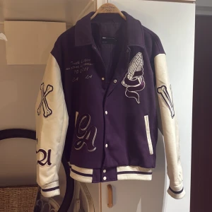 Lila Varsity jacka från ASOS Design - Säljer en fet lila och vit varsityjacka från ASOS Design med broderade detaljer, oversized i stilen och skön o använda säljer den för använder den aldrig