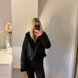 Svart läder/päls jacka med dragkedja - Säljer en svart jacka med mjuk fuskpäls på krage, ärmslut och nederkant. Jackan har en större passform och silverfärgade dragkedjor framtill och på fickorna. Perfekt för kalla dagar då den är väldigt varm. Aldrig använd (prislapp kvar). Storlek S, sann i storlek💞