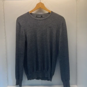 Grå stickad tröja från J.Lindeberg - Säljer en stilren grå stickad tröja från J.Lindeberg i storlek L. Tröjan har rund halsringning, lång ärm och ribbade muddar vid ärmslut och nederkant. Perfekt för lager-på-lager och enkel att matcha med jeans eller chinos.