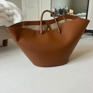 Little liffner - Tulip tote  - Tulip tote bag från Little Liffner i storlek Large, färg Camel. Väskan är sparsamt använd men har ett litet slitage på ena handtaget, se sista bilden. Rymmer dator mm perfekt för skola eller jobb. Dustbag kommer med vid köp. 