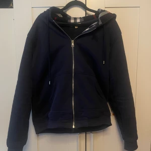 Burberry Zip hoodie  - Säljer en marinblå hoodie från Burberry med hel dragkedja och klassisk rutig insida i huvan. Priset går att diskutera vid snabb affär.