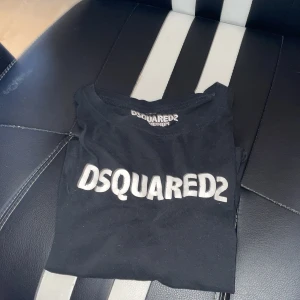 Svart DSQUARED2 t-shirt i bomull - Svart t-shirt från DSQUARED2 i storlek medium. Klassisk modell med rund hals och vit logotyp tryckt framtill. Tillverkad i mjuk bomull och har korta ärmar. Perfekt för dig som gillar stilrena och trendiga plagg med tydlig branding. Passar dig som är mellan 170-175🙌🙌