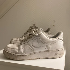 Nike Air Force 1 vita sneakers - Klassiska Nike Air Force 1 sneakers i helvitt skinn med perforerad tå och snörning. Snygg och tidlös modell med låg profil och rund tå. Perfekta för dig som gillar streetstyle och vill ha en ikonisk sneaker i garderoben. Jag säljer de då de är förstora på mig.