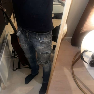 Nudie jeans slitna slim fit  - Säljer ett par blå slim  jeans med rejält slitna detaljer och stora hål över knäna. Jeansen har klassisk femficksdesign, låg midja och är tillverkade i denim. Perfekt för dig som gillar en edgy och avslappnad stil. Nudie jeans pris ej hugger i sten så buda på