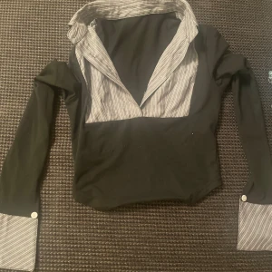 Svart henley med randiga detaljer - Väldigt fin och elegant skjorta. Är använd bara fåtal gånger