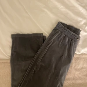 Grå mjukisbyxor från Gina Tricot - Mysiga grå mjukisbyxor från Gina Tricot i mjukt och stretchigt material. Byxorna har resår i midjan med metallöljetter framtill och raka ben. Perfekta för chill dagar eller när du vill vara extra bekväm. Saknar knytband