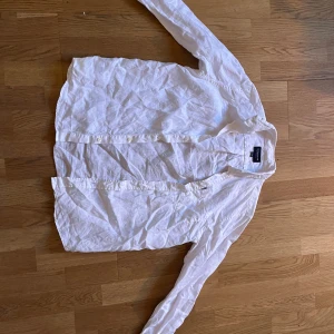 Vit linneskjorta från Lexington - Säljer en klassisk vit skjorta från Lexington i 100% linne. Skjortan har lång ärm, bröstficka och knäppning framtill. Perfekt för en clean och fräsch look, med snygg Lexington-detalj vid fickan. Passar dig som gillar stilrena plagg med premiumkänsla.