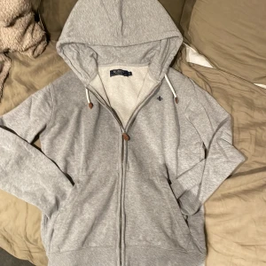 Grå hoodie från Morris - Säljer en stilren grå hoodie från Morris med dragkedja. Den har inte används mkt och nypris ca 1500kr. Snabb affär kan priset diskuteras
