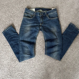 Blå jeans från Dondup, storlek 27 - Snygga blå jeans från Dondup med klassisk femficksdesign. Jeansen har raka ben, kontrastsömmar och läderpatch med logga bak i midjan.