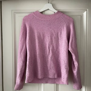Ljusrosa stickad tröja Vero Moda - Supermysig ljusrosa stickad tröja från Vero Moda. Tröjan har en rund halsringning, ribbade muddar och är långärmad. Perfekt för lager-på-lager och passar till både jeans och kjol. Enkel och stilren design som är lätt att matcha.