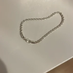 Snyggt tvinnat silverarmband - Stilrent armband i silverfärg med tvinnad kedja och klassiskt lås. Perfekt accessoar för att lyfta din outfit med en enkel men elegant touch.