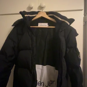 Svart pufferjacka från Calvin Klein Jeans - Säljer en svart pufferjacka från Calvin Klein. Då jackan blivit för liten. Den är använd väldigt sparsamt och kommer i ett jättebra skick!😀
