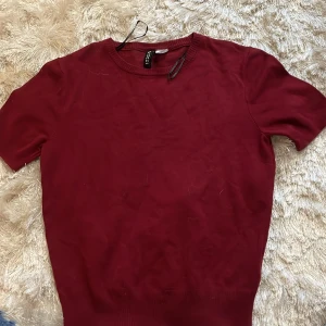 Vinröd kortärmad tröja H&M Divided XS - Vinröd tröja från H&M Divided i storlek XS. Modellen har korta ärmar, rund halsringning och är tillverkad i mjuk bomull. Perfekt för dig som gillar en enkel och stilren look med en pop av färg.