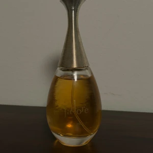 J'adore Eau de Parfum - En ikonisk parfym från Dior med elegant design. Perfekt för dig som vill sticka ut och addera en lyxig touch till din stil. Flaskans innehåll syns tydligt, men volym och ingredienser framgår inte på bilderna. Inte äkta 