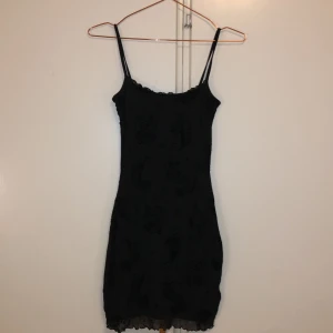 Svart kortklänning med tiger-mönster H&M - Supersnygg svart kortklänning från H&M Divided med tunna axelband och unikt tiger-mönster i sammet. Klänningen har en figurnära passform och vågig kant nertill. Använd ca 3 gånger och väldigt bra skick!!! Strl xxs.