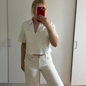 Vit croppad jeans topp - Säljer en vit croppad blus med kort ärm och stor krage i jeanstyg. Helt ny med alla prislappar kvar