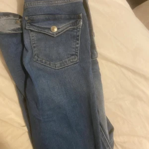 Blå jeans från 157  - Snygga blå jeans från 157 med klassisk femficksdesign, dragkedja och knapp framtill. Jeansen har bootcut ben och normal passform, med lätt slitning och tvättade detaljer för en cool look. Perfekta till sneakers eller boots.