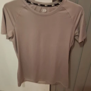 Lila sportig t-shirt från 157 - En stilren lila t-shirt från 157 med rund hals och korta ärmar. Tillverkad i ett mjukt och stretchigt syntetmaterial som andas, perfekt för träning. Enkel design utan mönster eller detaljer, passar dig som gillar en clean look.