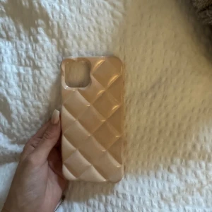 iPhone skal  - Stilrent quiltat skal i beige färg för iPhone. Skalet är i gott skick utan synliga repor eller skador. Ger din telefon ett elegant utseende och extra skydd mot stötar och repor.