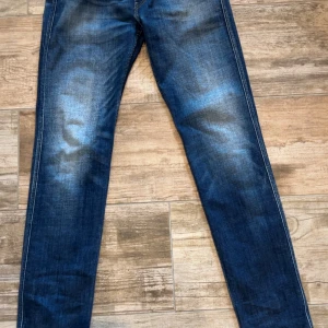 Replay Anbass slim fit jeans blå - Snygga blå Replay Anbass jeans i slim fit med klassisk femficksdesign och lätt slitna detaljer. Jeansen har normal midja och raka ben, tillverkade i mjukt denimtyg som sitter skönt hela dagen. Perfekta för dig som gillar en modern och stilren look.