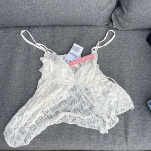 Vit spetsig linnetopp  - Säljer en superfin vit linnetopp med tunna axelband och vacker spets över hela toppen. Toppen har en feminin v-ringning och är lätt transparent, perfekt för lager-på-lager eller som statement-piece. Snygg och trendig design!