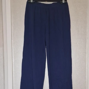 Mörkblå Justice League mjukisbyxor - Mörkblå mjukisbyxor från Justice League med resår i midjan och raka ben. Sköna och enkla att dra på, perfekta för chill dagar eller när du vill ha det bekvämt. Tillverkade i mjukt bomullsmaterial.