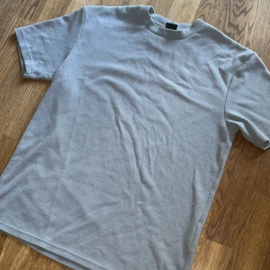 Grå t-shirt, relaxed fit - Enkel och stilren grå t-shirt i relaxed fit. T-shirten är kortärmad och har en diskret struktur i tyget som ger en cool känsla. 