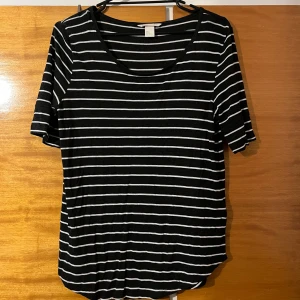 Svartvit randig t-shirt H&M - Svart t-shirt från H&M med vita horisontella ränder. Klassisk rund halsringning och korta ärmar. Skön och mjuk i bomullsmix, perfekt till jeans eller shorts. Enkel och stilren design som funkar året runt.
