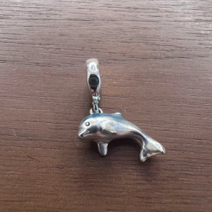 Berlock till Pandora armband - Hängande blå delfin berlock i silver till Pandora armband. Så gott som nytt. Använt färre än 10 gånger. (Armband ingår ej i priset)