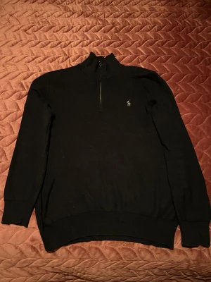 Svart half zip tröja Polo Ralph Lauren - Svart långärmad tröja från Polo Ralph Lauren i mjuk pima bomull. Klassisk half zip med ståkrage och diskret broderad logga på bröstet. Perfekt för dig som gillar stilrena och tidlösa plagg med snygg passform.