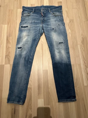 Blå Dsquared jeans - Säljer ett par blå jeans från dsquared  med coola slitningar och färgstänk på både fram- och baksida. Modellen heter Skinny Dan. Vid frågor eller funderingar är det bara att skriva.//Samuel 