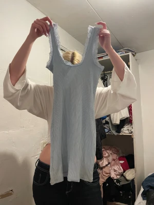 Ljusblå ribbad klänning från H&M Divided - Supersöt ljusblå kortklänning från H&M Divided i ribbad bomull med spetsdetaljer vid axelbanden och halsringningen. Ärmlös och figurnära passform som ger en fräsch och ungdomlig vibe. Perfekt för sommarens alla tillfällen!