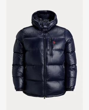 Svart pufferjacka från Polo Ralph Lauren - Snygg svart pufferjacka från Polo Ralph Lauren med glansig finish och röd logga på bröstet. Jackan har huva med snörning, flera dragkedjefickor och quiltad design. Perfekt för kalla dagar och har en modern, oversized look. Finns alla storlekar 