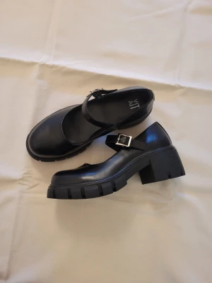 Mary Janes skor  - Svarta oanvända platåskor med knäppe.