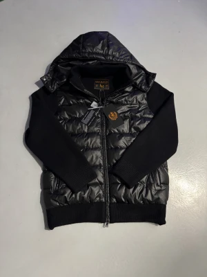 Leon Marcèl Hybrid Jacket  - Leon Marcél Hybrid Jacket i toppskick. Modern passform, lätt och varm med avtagbar luva – perfekt för vardag och layering. Kan köpas här eller på www.leonmarcel.eu med Klarna Pay Later + 12 andra betalningsmetoder.