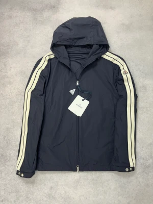 Moncler olan windbreaker jacket - – Condition: 10/10 - brand new  - Size: 4/XL  – Retail price: 11 575 SEK  Please note that Moncler runs small, we recommend going up one size from your usual size.