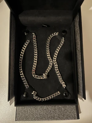 Kejsar silver kedjehalsband - Snyggt och robust kedjehalsband från Kejsar i silver. Länkarna är platta och breda med en modern, chunky look. Levereras i exklusiv svart ask med guldfärgad logga. Perfekt för dig som gillar statement-smycken.