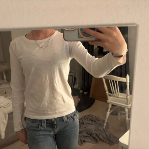 Vit långärmad tröja  - En enkel och stilren vit långärmad tröja. Modellen har rund hals och en normal passform som sitter snyggt till jeans eller andra favoritplagg. Perfekt för dig som gillar basic men snygg stil och vill ha en basic topp i garderoben.