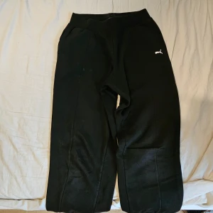 Svarta mjukisbyxor från Puma - Svarta mjukisbyxor från Puma med elastisk midja och muddar vid bensluten. Ena benet har stor vit Puma-logga där bak och den andra har en liten logotyp. Sköna!