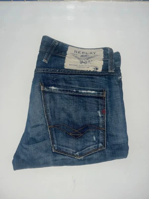 Replay Anbass jeans - Säljer ett par Replay Anbass jeans i klassisk blå tvätt med snygga slitningar och kontrastsömmar. Modellen har raka ben och normal passform. Midja 42cm, längd 106cm. JAG SKICKAR EJ FLER BILDER NÄR JAG BÄR JEANSEN! för storleksguide hänvisar jag till måtten och för bättre inblick i passformen rekommenderar jag att googla på modellnamnet. kolla måtten noggrant :) 65