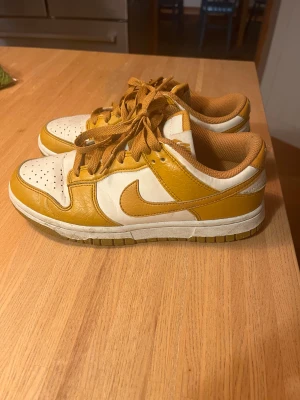 Nike Dunk Low i vitt och gult - Säljer ett par Nike Dunk Low sneakers i vitt och senapsgult läder med matchande gula skosnören och innerfoder. De är knappt använda, super bra skick! Pris går att diskutera 