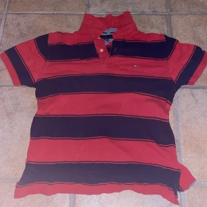 Tommy Hilfiger piké - Fet Tommy Hilfiger tröja som inte passar mig längre. Den är röd och mörkblå randig och är storlek M men passar S