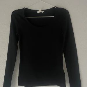 Svart långärmad topp från H&M XS - En svart långärmad topp från H&M i storlek XS. Modellen har rundad halsringning och är figurnära. Materialet är mjukt och stretchigt med 95% bomull och 5% elastan, vilket gör den bekväm och följsam. Perfekt att styla med jeans eller kjol.