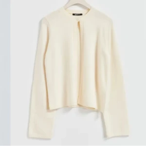 Beige stickad kofta från Gina Tricot - Säljer en stilren beige stickad kofta från Gina Tricot. Koftan har rund halsringning, långa ärmar och en minimalistisk design utan synliga knappar. Perfekt att slänga över en t-shirt eller klänning för en clean look. Size s