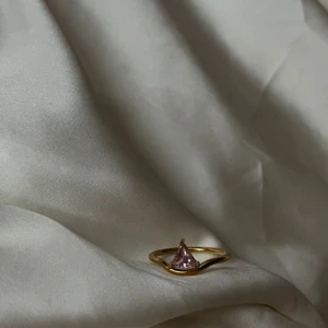 Guldring med rosa och klara stenar - Två stilrena guldringar, en med en triangelformad rosa sten och en med två fyrkantiga klara stenar. Båda har tunn guldfärgad ring och modern design som sticker ut. Perfekt för dig som gillar unika detaljer och färgklickar i din stil. Stianless steel 18k guldpläterad 🩷💞