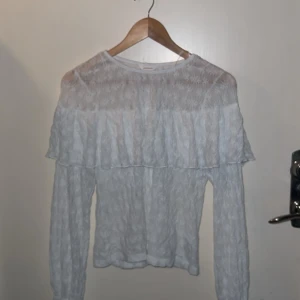 Vit blus med volang från dobber  - Supersöt vit blus från dobber i storlek S. Blusen har långärmade ärmar, volang över axlar och bröst samt ett diskret blommigt mönster i tyget. Tunt och lätt material som ger en romantisk vibe. Perfekt att styla med jeans eller kjol för en trendig look. Köpte för 600 kr och har använt en gång. 