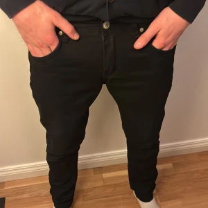 Svarta Diesel jeans, slim fit - Säljer ett par svarta jeans från Diesel med snygga detaljer och klassisk femficksdesign. Jeansen har smal passform och är tillverkade i mjukt denim-material med metallknappar och Diesel-logga på fickan. Perfekt för dig som gillar stilrena och moderna jeans. Nypris: 1400 ALDRIG ANDVÄNDA DISKUTERBART PRIS
