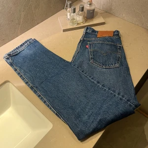 Levi's 501 blå jeans W29 L32 - Klassiska Levi's 501 jeans i blå denim med raka ben och knappgylf. Byxorna är i använt bra skick. Midjemåttet är 29 och längden är 32.