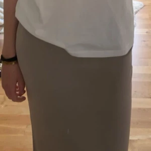 Beige långkjol - Säljer en beige långkjol från 157 i storlek S. Kjolen har en rak och enkel design med resår i midjan och mjukt material. Bekväm och snygg! I väldigt fint skick